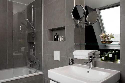 a bathroom with a sink and a mirror and a shower at Hotel ZOE by AMANO in Berlin