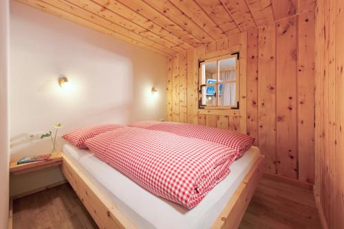 ein Bett in einem Zimmer mit einer Holzwand in der Unterkunft Martinshof in Sankt Johann in Tirol