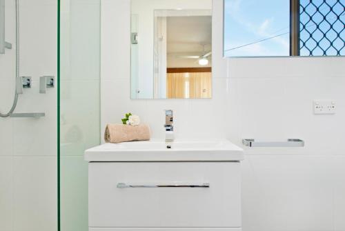 a white bathroom with a sink and a shower at Beauty at the Beach - modern beachfront apartment in Port Macquarie