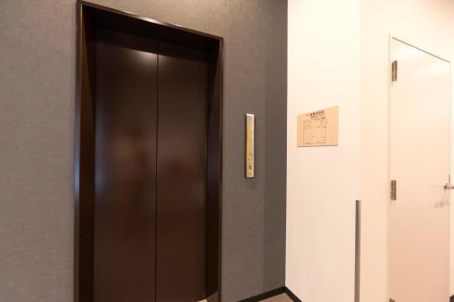a brown elevator in a building with a sign on the wall at Mikasa Tennen Onsen Taikonoyu Sparesort Hotel Taiko Bettei Hatago in Iwamizawa