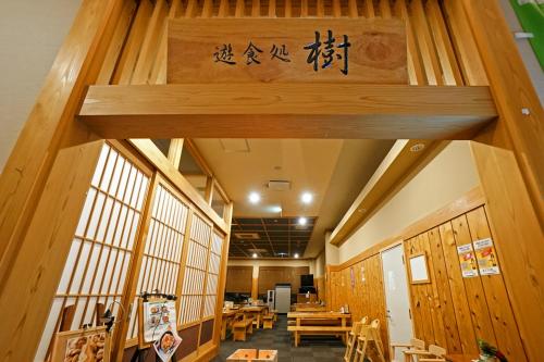 a restaurant with wooden walls and tables and a sign at Mikasa Tennen Onsen Taikonoyu Sparesort Hotel Taiko Bettei Hatago in Iwamizawa