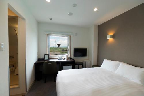 a hotel room with a bed and a desk and a window at Mikasa Tennen Onsen Taikonoyu Sparesort Hotel Taiko Bettei Hatago in Iwamizawa