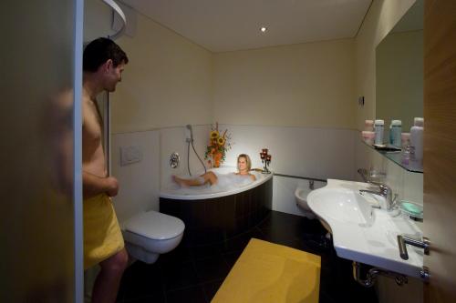 a man in a bathroom with a baby in a bath tub at Residence Garni Alpenstern in Resia