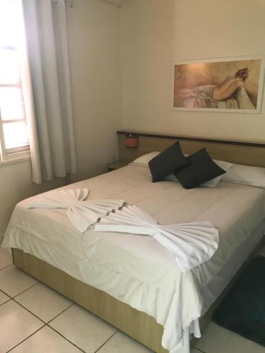 a bedroom with a large bed with white sheets at Amoreiras Hotel Pousada in Maresias