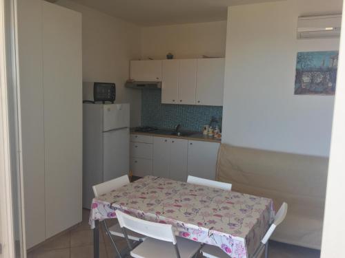 a kitchen with a table and white cabinets and a table and chairs at Casa Marea in Marzamemi
