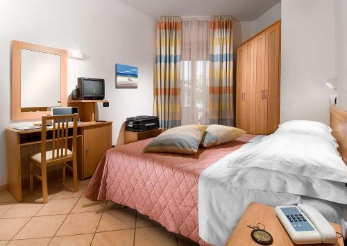 a bedroom with a bed and a desk with a computer at Hotel Savoia in Cesenatico