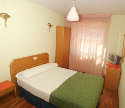 Dormitorio pequeño con cama con manta verde en Hostal Arlanzón, en Burgos