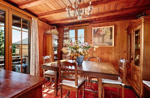 uma sala de jantar com uma mesa de madeira com flores em Le Liseron em Leysin