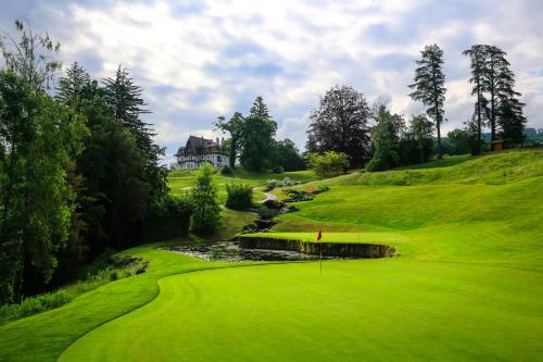 a green golf course with a house in the background at Hôtel Ermitage in Évian-les-Bains