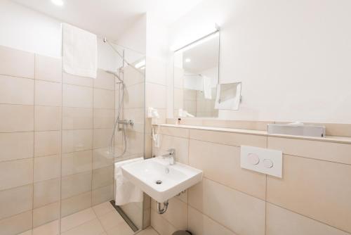 a white bathroom with a sink and a mirror at Hotel & Gasthaus Löwen in Waldkirch