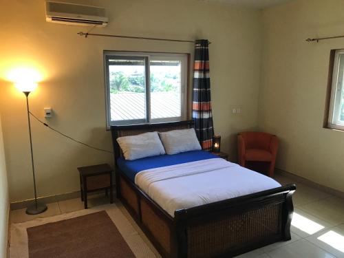 a bedroom with a bed and a window and a lamp at Royal German Apartments in Accra