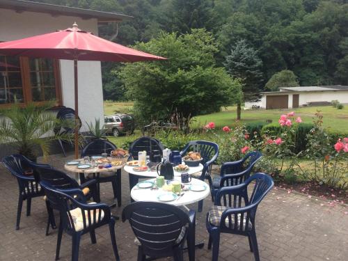 un groupe de tables et de chaises avec un parapluie dans l'établissement Pension Waldfrieden, à Thale