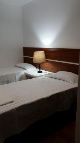 two beds in a room with a lamp on a table at Nossa Casa na Aldeia in Viseu