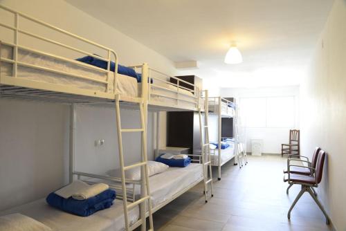 a room with three bunk beds and a chair at Albergue Mar de Fora in Finisterre