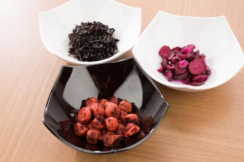 drei Schüsseln Essen auf einem Holztisch in der Unterkunft Hotel Route-Inn Saiki Ekimae in Saiki