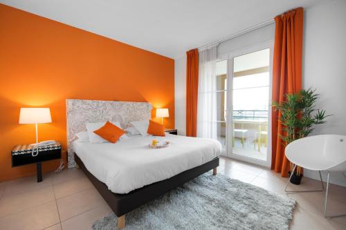 a bedroom with a bed with an orange wall at Privilège Appart-Hôtel Domaine De Mai - parking gratuit in Mougins