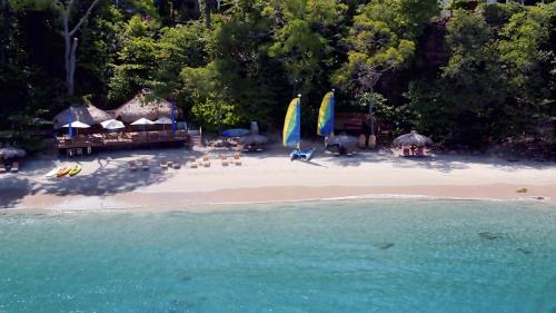 a beach with umbrellas and chairs and people on the beach at Cap Maison Resort & Spa in Cap Estate
