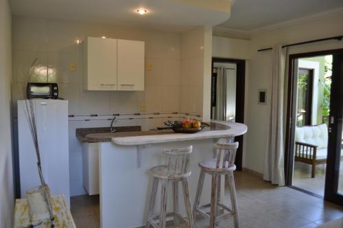 a kitchen with a counter with stools and a refrigerator at Recanto da Mata Pipa in Pipa