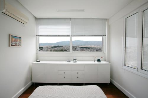 een witte badkamer met een wastafel en een raam bij Mind-blowing Acropolis View Apt in Athene
