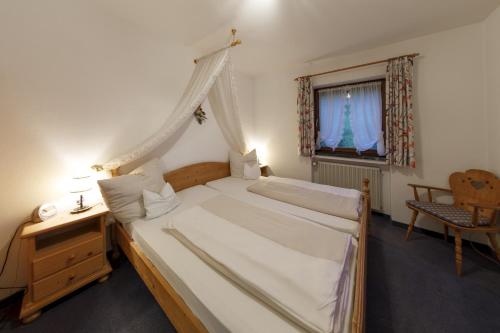 a bedroom with a canopy bed and a window at Hotel & Gasthof Fraundorfer in Garmisch-Partenkirchen
