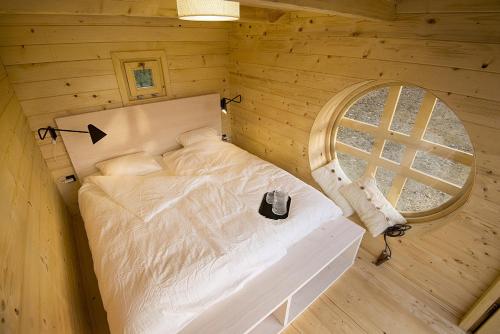 a bed in a wooden room with a round window at Green Resort Glamping in Radlje ob Dravi