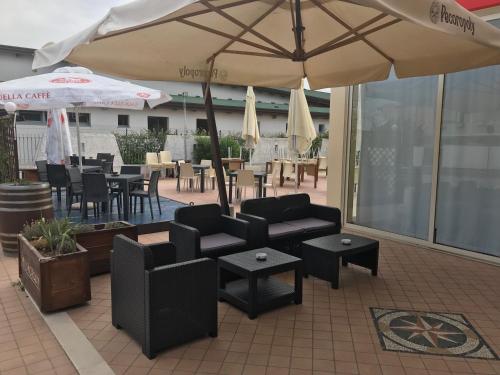 a patio with couches and tables and an umbrella at Rosso Di Sera in Citta' Sant'Angelo
