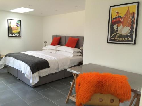 um quarto com uma cama e uma secretária com uma almofada laranja em The Garage em Banbury