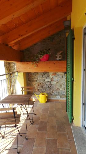 a patio with a table and chairs and a stone wall at Agriostello delle Langhe in Farigliano