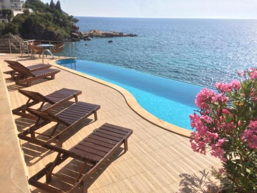 a swimming pool with lounge chairs and the ocean at Resort Stikovic in Dobra Voda