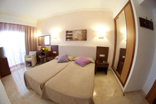 una camera con un grande letto e un grande specchio di Hotel Cala Gat a Cala Ratjada