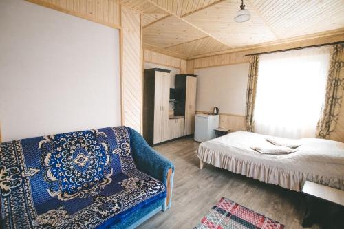 a bedroom with a bed and a couch and a window at Skarbivka in Vorokhta