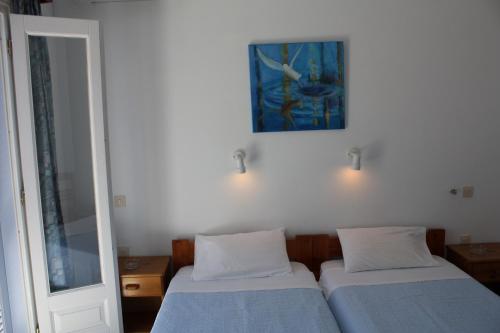 a bedroom with two beds and a painting on the wall at Sanoudos in Naxos Chora