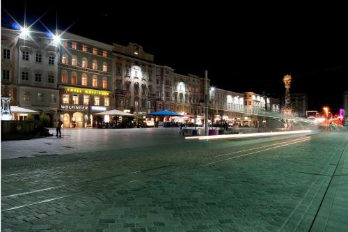 eine Stadtstraße in der Nacht mit Gebäuden und Lichtern in der Unterkunft Austria Classic Hotel Wolfinger - Hauptplatz in Linz