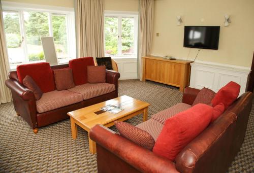 a living room with leather furniture and a flat screen tv at Quorn Country Hotel Leicester in Loughborough
