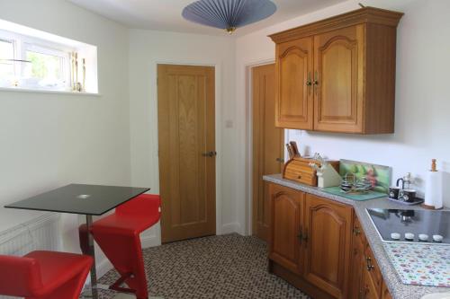 a kitchen with a table and a red stool in it at Pear Tree House Studio in Ely