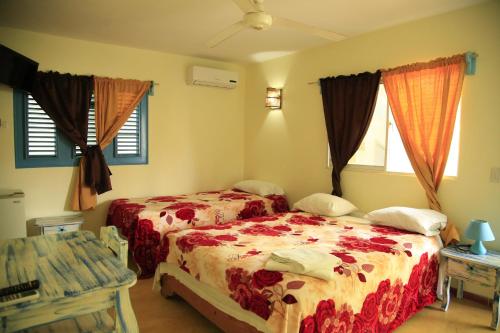 a bedroom with two beds and a table and windows at Casa Brisa Mar Hotel in Las Terrenas