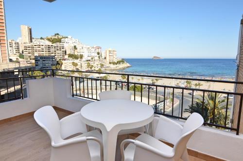 a white table and chairs on a balcony with the beach at Apartamentos Odysea By Apartamentos Valentia in Cala de Finestrat