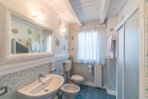 bagno con lavandino, servizi igienici e specchio di Le Residenze del Tenore a Romano di Lombardia