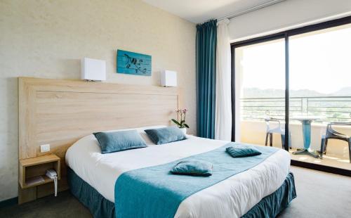 a bedroom with a large bed with blue pillows on it at Logis Hotel Restaurant La Porte des Cévennes in Anduze