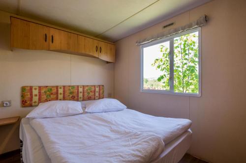 a bedroom with a white bed and a window at Nemeth Camping Spa & Pool Access in Sovata