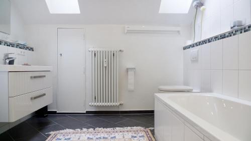 a white bathroom with a tub and a radiator at Ekatarina Apartments in Baden-Baden