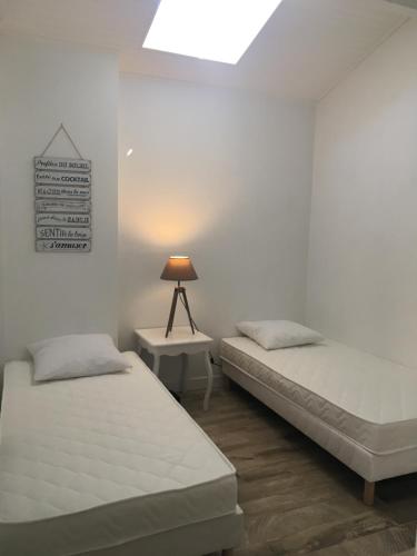 two beds in a room with a lamp on a table at Appartement Côté Bassin in Andernos-les-Bains