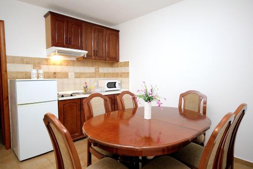 a kitchen with a wooden table and a white refrigerator at Apartmani More in Sveti Stefan