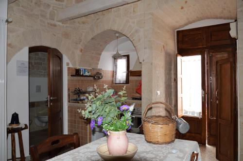 Una cocina con una mesa con un jarrón de flores encima. en Trullo di Giovannina Casa Vacanza, en Alberobello