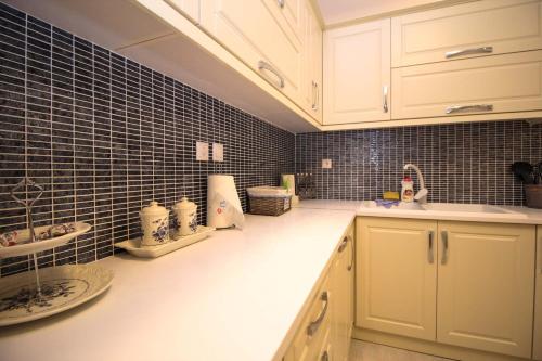 a kitchen with white cabinets and black tiled walls at Villa Aleandro in Ksamil