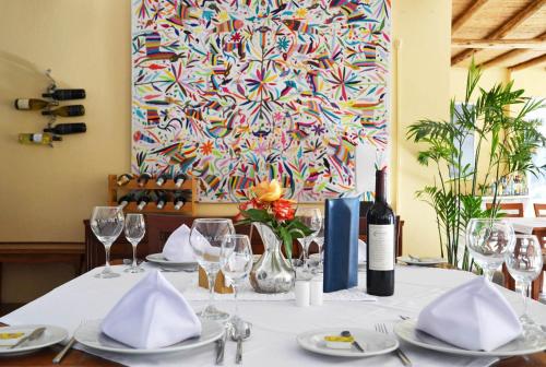 una mesa con platos y vasos y una pintura en Hotel Los Palomos, en Lunahuaná