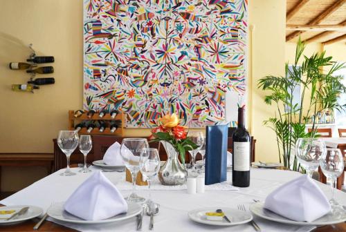 a table with plates and glasses and a painting at Hotel Los Palomos in Lunahuaná