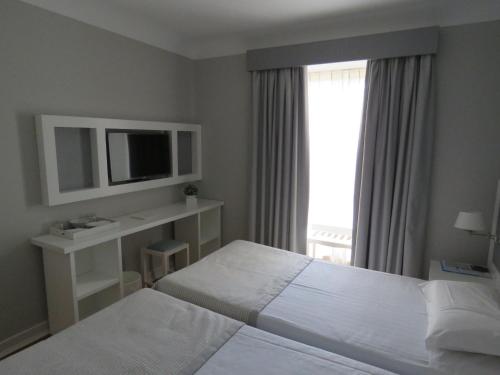a hotel room with two beds and a television at Grande Hotel das Caldas da Felgueira in Caldas da Felgueira