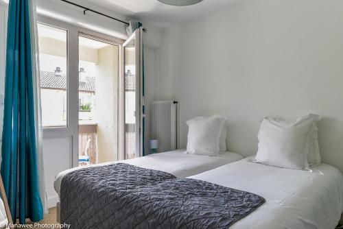 two beds in a room with a window at La Roseraie du Lac in Annecy