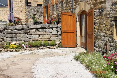 a stone building with a wooden door and a stone wall at Chambres d'hôtes Entre Dolmens et Fontaines in Buzeins